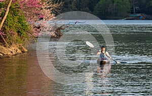 Man in small white water kayak coming towards the viewer on lake