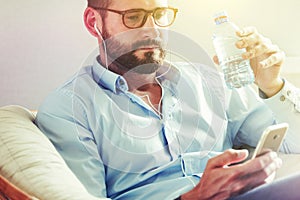 Man with smart phone drinking water