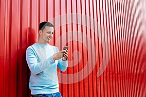 Man with smart phone in hands on the background of red wall