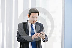 Man on smart phone - young businessman in airport. Casual urban professional business man using smartphone.
