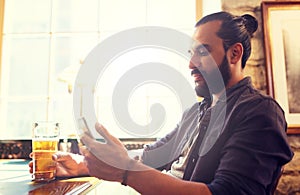 Man with smartphone drinking beer at bar or pub