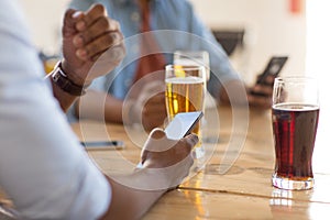 Man with smartphone drinking beer at bar or pub