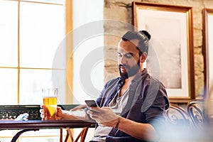 Man with smartphone drinking beer at bar or pub