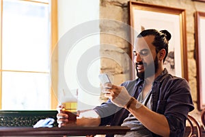 Man with smartphone drinking beer at bar or pub