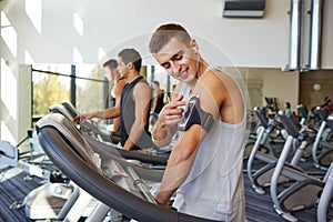 Man with smartphone exercising on treadmill in gym