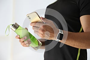 Man with smartphone and fitness tracker indoors, closeup
