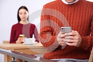 Man with smartphone ignoring his girlfriend in cafe. Relationship problems