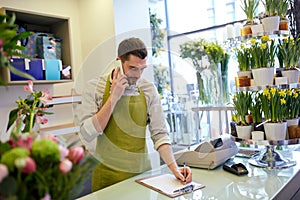 Man with smartphone making notes at flower shop