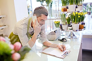 Man with smartphone making notes at flower shop