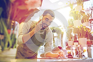 Man with smartphone making notes at flower shop