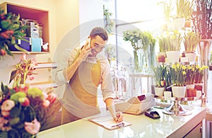 Man with smartphone making notes at flower shop