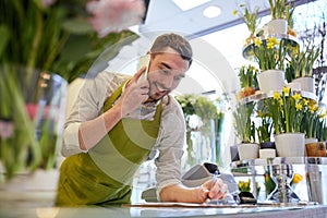 Man with smartphone making notes at flower shop