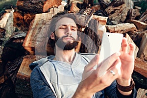 Man with smartphone on pile of wood