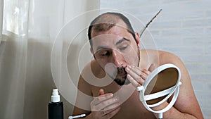 The man smears his face with lotion.A handsome man takes care of the skin on his face, applies a moisturizer to the face