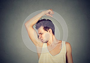 Man, smelling, sniffing his armpit, something stinks bad, foul odor photo