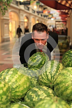Man smelling watermellons in shopping-centre