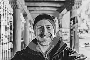 Man smiles at camera in foreground against dynamic breezeway in black and white photo