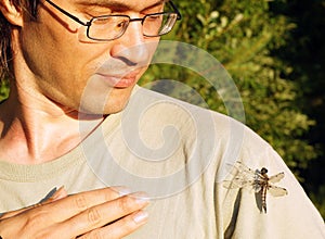 Man smiles friendly to dragonfly