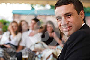 Man smiles over his shoulder surrounded by friends