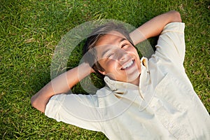 Man smiling as he lies with both hands behind his neck