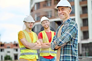 Man smiling at camera and workers behind