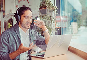 Man smiling having a video chat at laptop screen, explaining something