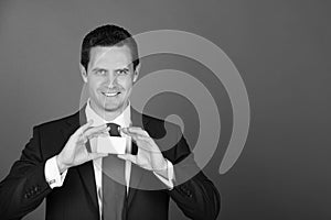 Man smiling and holding card in business suit on blue