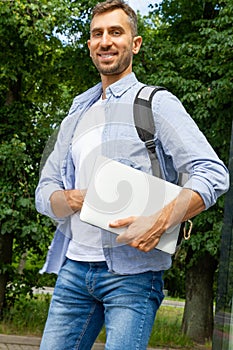 Man Smiling and holding a laptop in his hands.