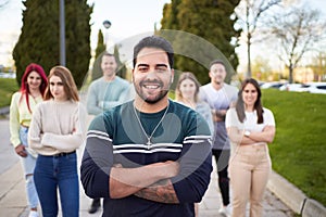 Man smiling looking at the camera while standing in front of a group of people.