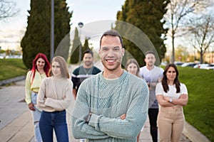 Man smiling looking at the camera while standing in front of a group of people.