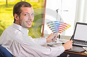 Man smiling to camera and working on laptop while