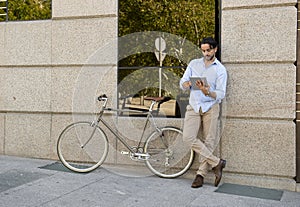 Man smiling using internet with digital tablet pad on vintage cool retro bike