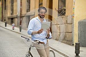 Man smiling using internet with digital tablet pad on vintage cool retro bike