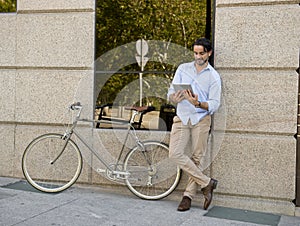 Man smiling using internet with digital tablet pad on vintage cool retro bike