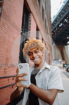 Man smiling in vintage clothing on street with mobile phone for selfie