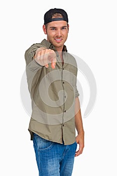 Man smiling and wearing baseball hat backwards and pointing