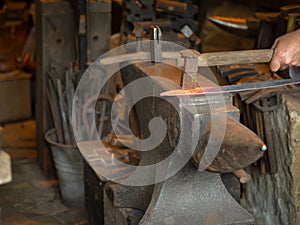 Man smithing a red-hot piece of metal on an anvil