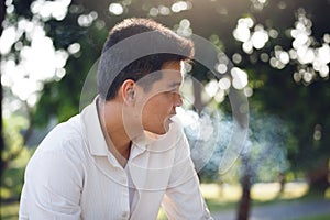 Man smoking and blurred tree Background