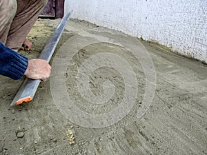 A man smooths the surface of a cement-sand mixture with an aluminium plasterers feather edge tool. Preparation of the site for