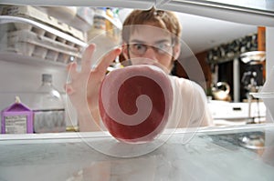 Man snatching apple from fridge