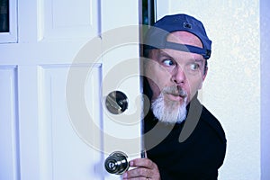 Man sneaking into house from doorway. photo