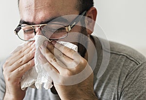 Man sneezing into tissue paper