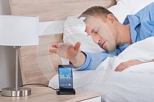 Man Snoozing Alarm On Mobile Phone Screen photo
