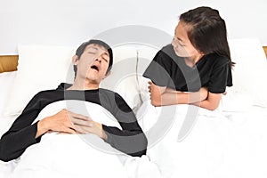Man snoring in bed while his little girl covering her ears with