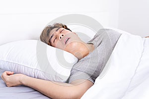 Man snoring loudly because of tired from work, sleep apnea lying in the bed. Healthcare medical or daily life concept