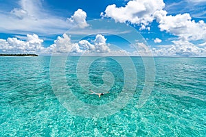 Man snorkeling in clear tropical waters in front of exotic island