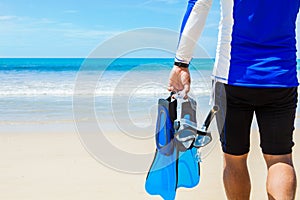 Man with snorkeling gear in hands going to sea on beach