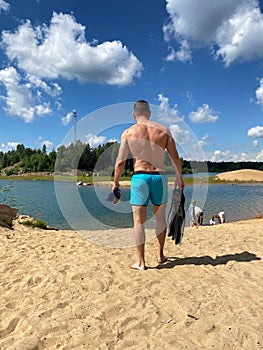 Man with snorkeling gear in hands going to sea on beach