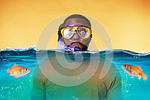 Man with snorkeling mask is scared to go underwater. yellow background