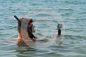A man snorkels with an action camera in the sea, close-up photo